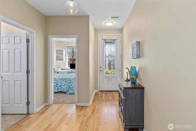 doorway with light wood-style floors and baseboards