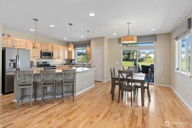 kitchen with stainless steel appliances, a kitchen island, light wood finished floors, recessed lighting, and light brown cabinets