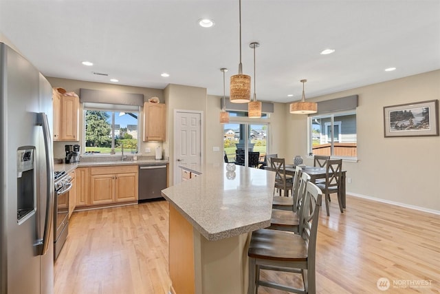 kitchen with appliances with stainless steel finishes, light brown cabinets, light wood finished floors, recessed lighting, and a center island