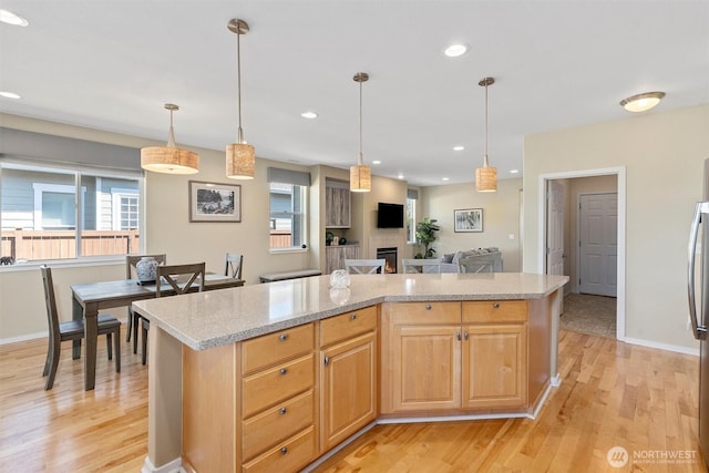 kitchen with healthy amount of natural light, light wood-style flooring, light brown cabinetry, recessed lighting, and decorative light fixtures