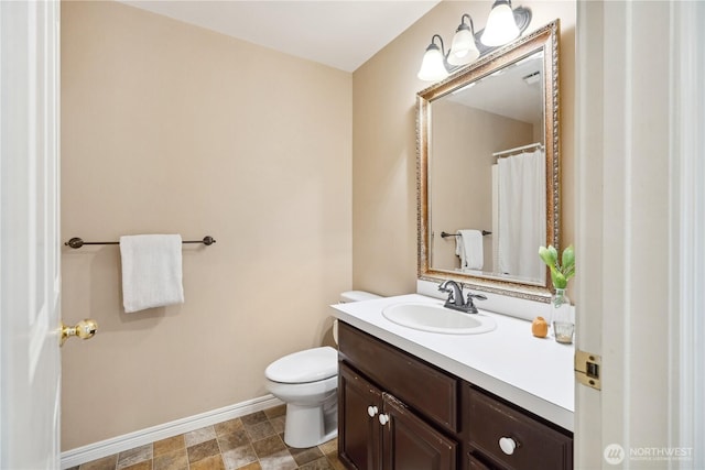 bathroom featuring baseboards, toilet, and vanity