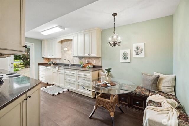 kitchen with white dishwasher, dark wood finished floors, decorative backsplash, and a chandelier