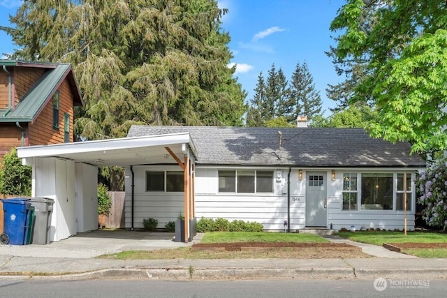 view of front of home with a chimney, an attached carport, asphalt driveway, and a shingled roof