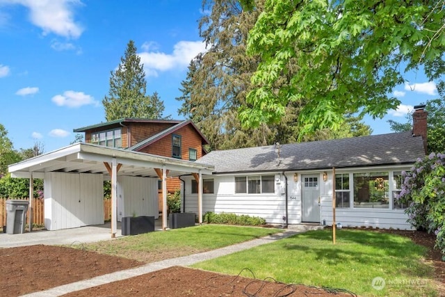 view of front of home featuring concrete driveway, a front yard, a chimney, and an attached carport