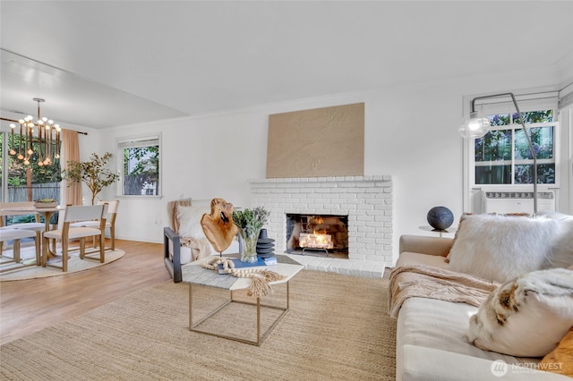 living area featuring a chandelier, wood finished floors, a fireplace, ornamental molding, and cooling unit