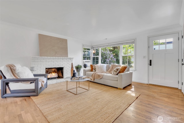 living area with ornamental molding, wood finished floors, and a fireplace