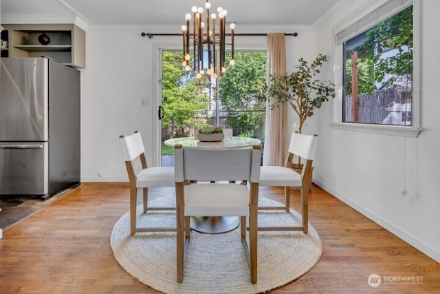 dining area featuring crown molding, a chandelier, baseboards, and light wood finished floors