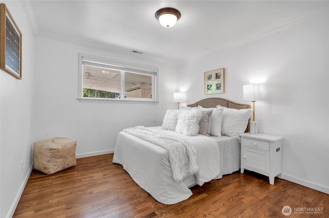bedroom with crown molding, wood finished floors, and baseboards