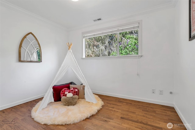 recreation room with baseboards, wood finished floors, and ornamental molding