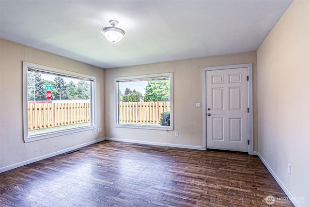 unfurnished room with dark wood-style floors and baseboards