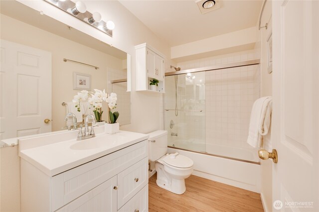 18210 73rd Ave NE Unit 101, Kenmore, WA 98028 - full bathroom featuring wood finished floors, toilet, vanity, and bath / shower combo with glass door
