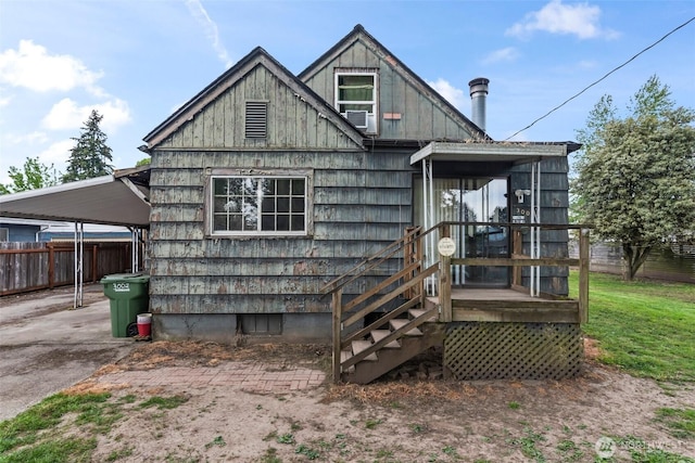 rear view of property with fence, board and batten siding, and an attached carport