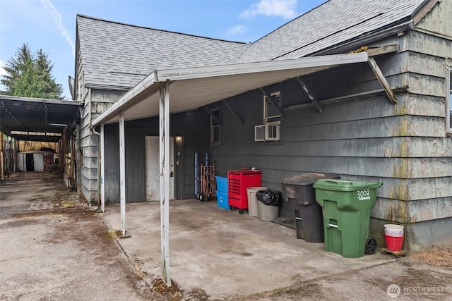 view of side of home featuring an attached carport, roof with shingles, concrete driveway, and cooling unit