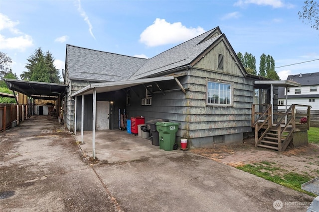view of property exterior with roof with shingles, a carport, driveway, a wooden deck, and cooling unit