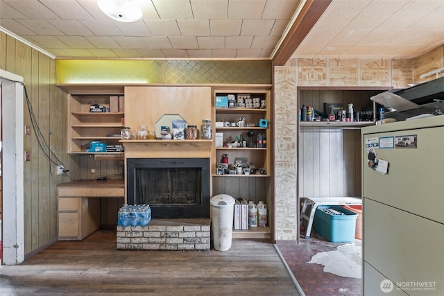 living room featuring wooden walls, wood finished floors, a fireplace with raised hearth, and ornamental molding