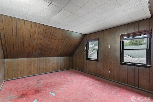 bonus room featuring wood walls, carpet floors, and vaulted ceiling