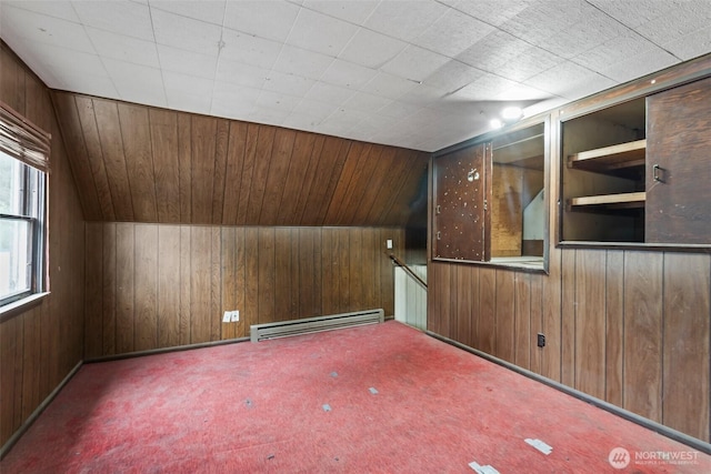 carpeted empty room featuring a baseboard heating unit, wood walls, and lofted ceiling