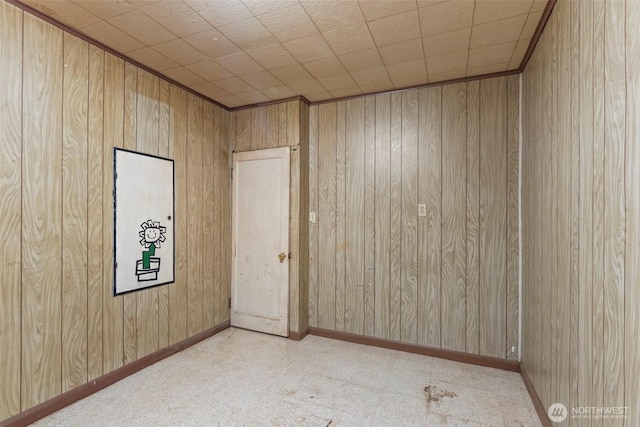 unfurnished room featuring wood walls and baseboards