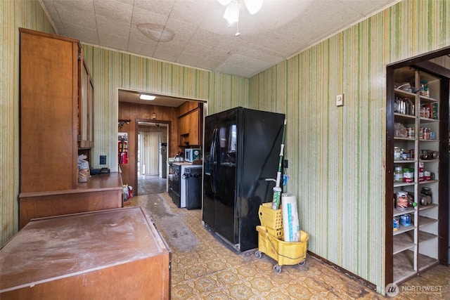kitchen with black fridge with ice dispenser, wallpapered walls, brown cabinetry, stainless steel microwave, and ceiling fan