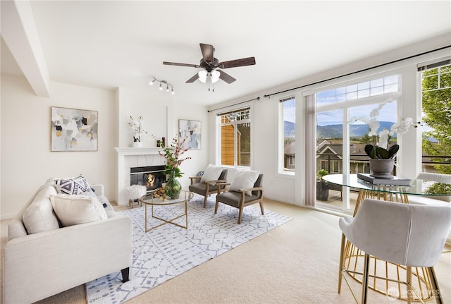 living area featuring ceiling fan, carpet floors, a tiled fireplace, a mountain view, and track lighting