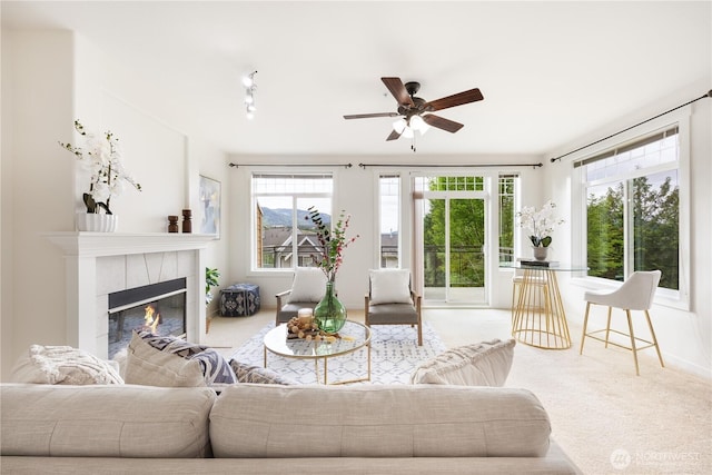 living area featuring a ceiling fan, a tile fireplace, and carpet floors