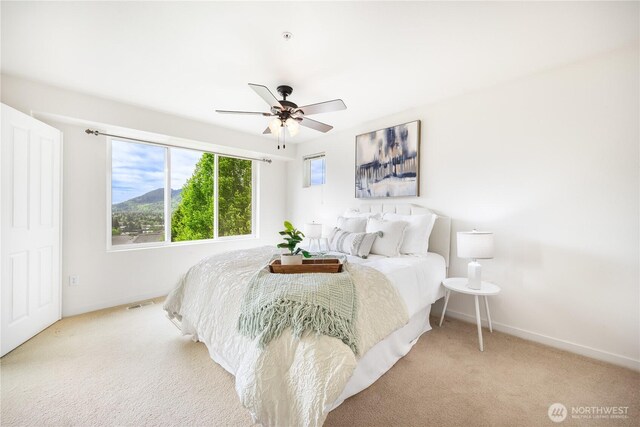 carpeted bedroom featuring multiple windows, baseboards, and ceiling fan