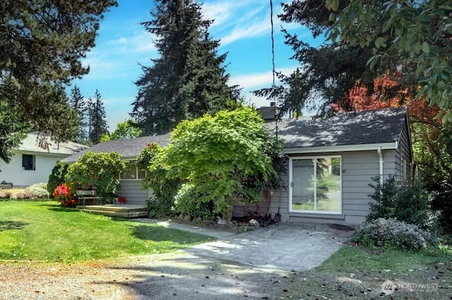 view of front of property featuring a front lawn and a shingled roof