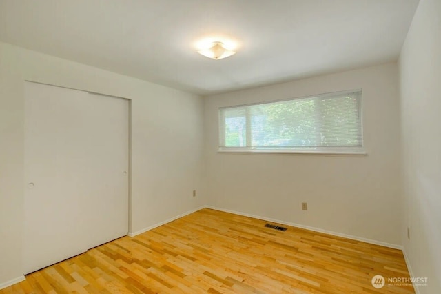 unfurnished bedroom with light wood-style floors, a closet, and baseboards