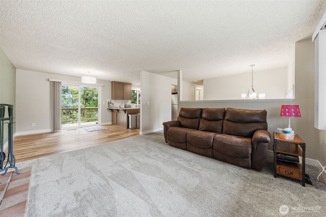 living area featuring light carpet, a textured ceiling, and baseboards