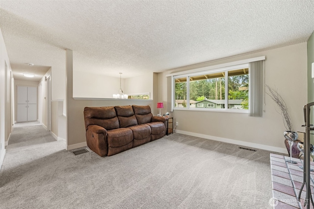 carpeted living area featuring a chandelier, baseboards, and a textured ceiling