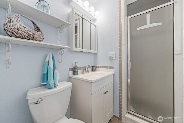 bathroom with a stall shower, toilet, and vanity