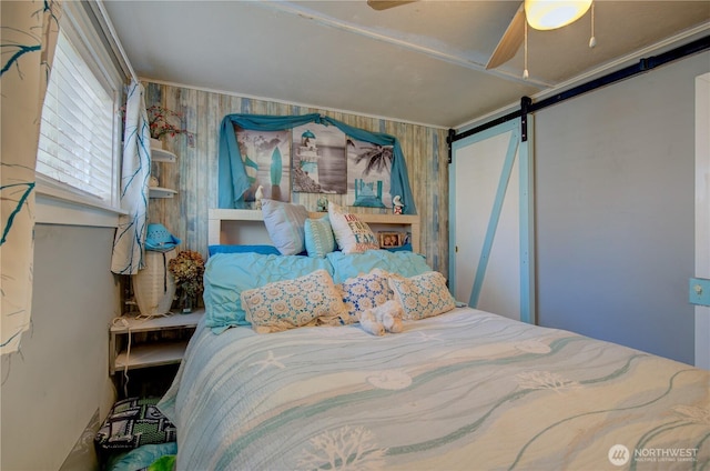 804 Pacific Ave N, Long Beach, WA 98631 - bedroom with a barn door, a ceiling fan, and wooden walls