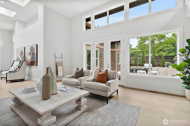 1038 Belfair Rd, Bellevue, WA 98004 - living room with a high ceiling, light wood-style floors, a skylight, french doors, and baseboards