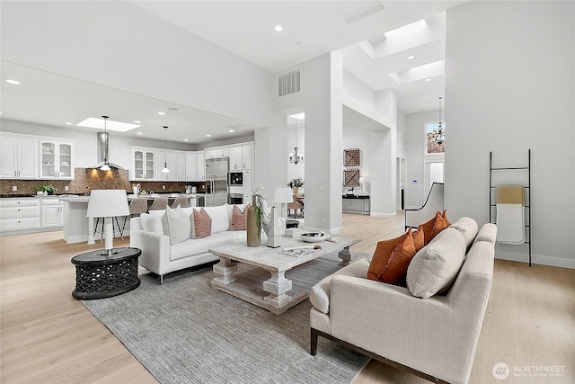 1038 Belfair Rd, Bellevue, WA 98004 - living area featuring light wood-style flooring, recessed lighting, a towering ceiling, baseboards, and a chandelier