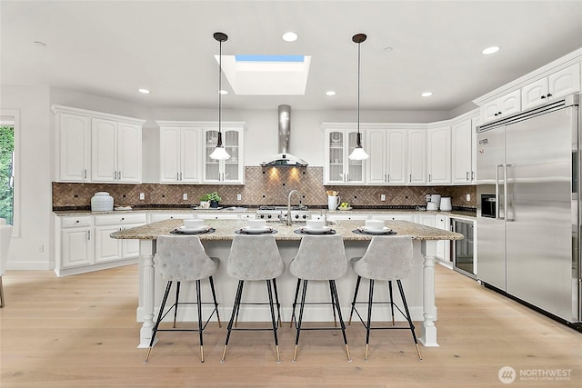 1038 Belfair Rd, Bellevue, WA 98004 - kitchen featuring stainless steel built in refrigerator, wall chimney range hood, wine cooler, a sink, and a kitchen bar