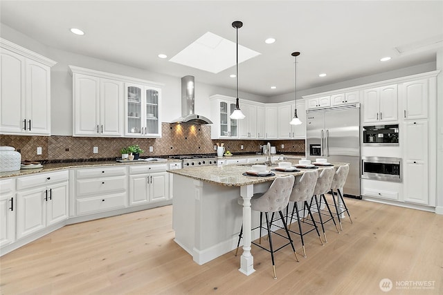 1038 Belfair Rd, Bellevue, WA 98004 - kitchen with built in refrigerator, wall chimney range hood, range, light wood finished floors, and glass insert cabinets