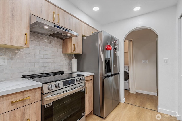 15623 NE 18th St Unit D201, Bellevue, WA 98008 - kitchen with stainless steel appliances, under cabinet range hood, light wood-style flooring, washer / clothes dryer, and arched walkways