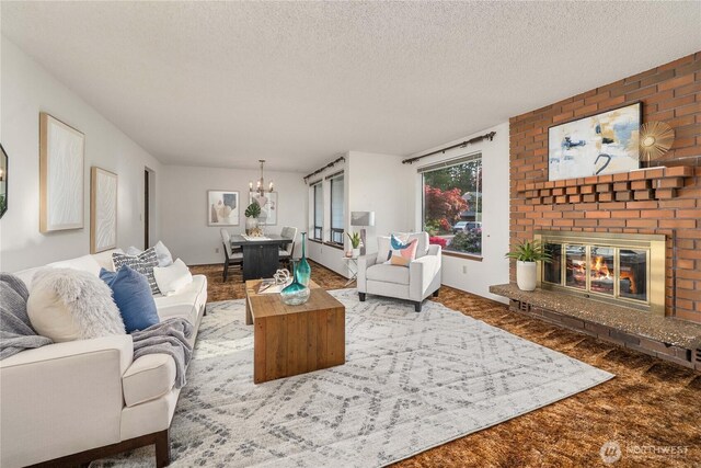 living room featuring a chandelier, a fireplace, and a textured ceiling