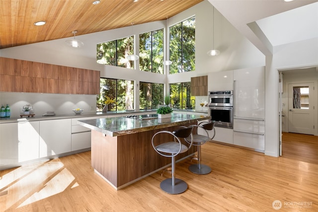 11819 73rd Pl NE, Kirkland, WA 98034 - kitchen with modern cabinets, double oven, high vaulted ceiling, a center island, and a kitchen breakfast bar