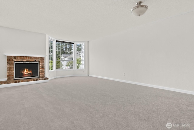 unfurnished living room with carpet flooring, baseboards, and a brick fireplace