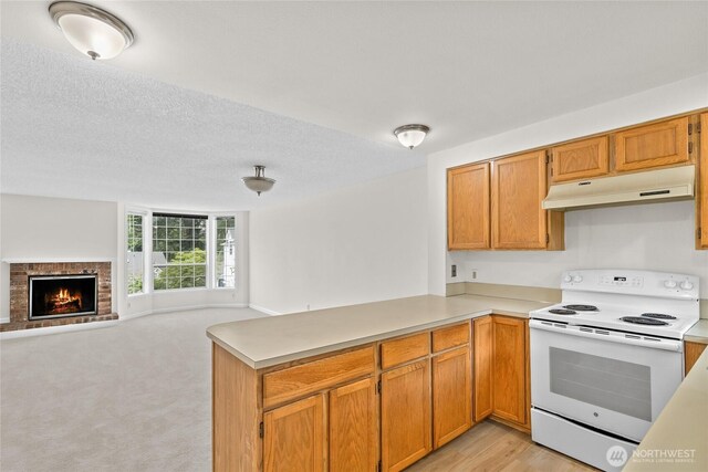 kitchen featuring white electric range, under cabinet range hood, a peninsula, open floor plan, and light countertops