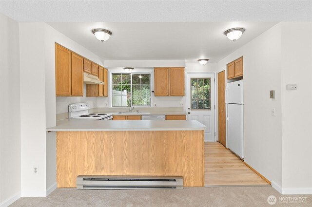 kitchen featuring white appliances, under cabinet range hood, a peninsula, a baseboard heating unit, and light countertops