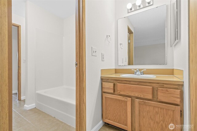 bathroom featuring tile patterned floors, vanity, baseboards, and shower / washtub combination