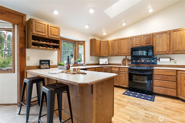 12013 Exeter Ave NE, Seattle, WA 98125 - kitchen featuring black appliances, a peninsula, a kitchen bar, a skylight, and lofted ceiling