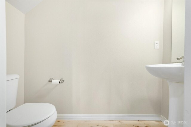 bathroom featuring toilet, baseboards, and a sink
