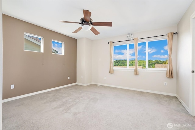 carpeted spare room with ceiling fan and baseboards