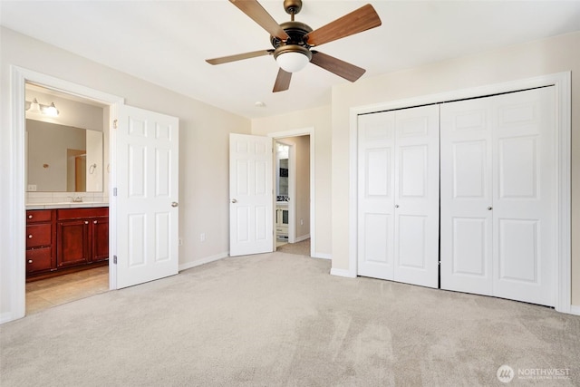 unfurnished bedroom with light colored carpet, baseboards, a closet, and connected bathroom