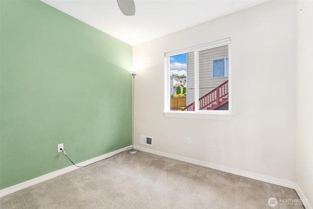 carpeted empty room featuring baseboards and a ceiling fan
