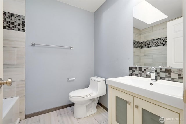 full bathroom featuring tiled shower, toilet, vanity, and baseboards
