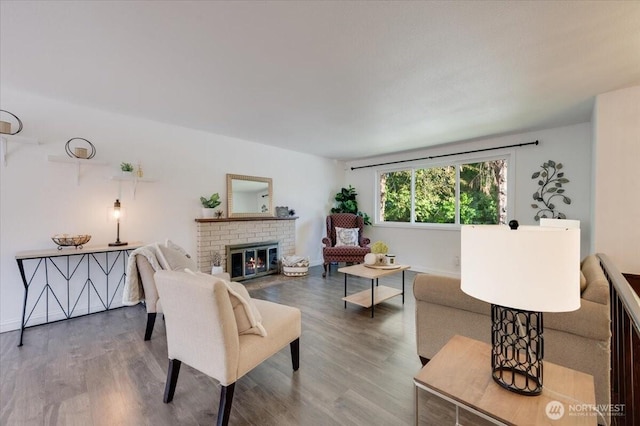 living room with wood finished floors, a brick fireplace, and baseboards